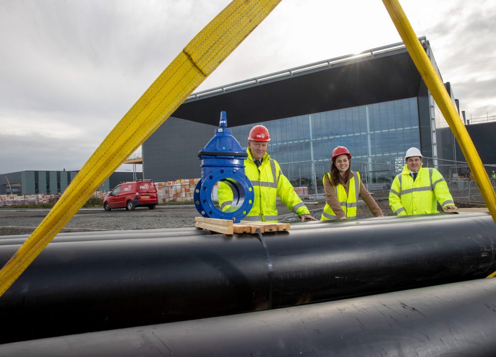 Scottish Government Cabinet Secretary for Finance and the Economy Kate Forbes in front of the heating network building along with other staff members, with the heating system pipes.