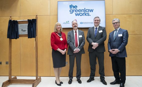 Photograph of The Greenlaw Works official opening plaque on the left, and standing on the right - from left to right and facing the camera, smiling - Provost Mary Montague, Council Leader Owen O'Donnell, Tom Arthur MSP, and Lord Offord of Garvel.
