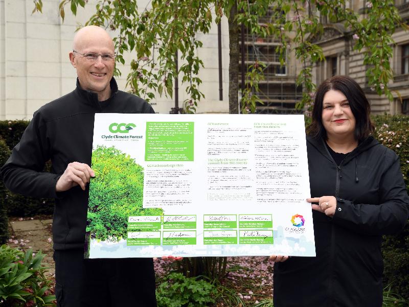 Max Hislop, director of Clyde Climate Forest, and Councillor Susan Aitken stand side by side holding the Clyde Climate Forest concordat signed by all eight council leaders.