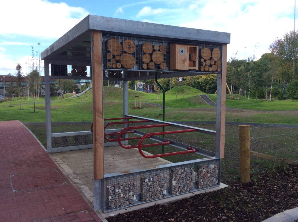 Close-up photograph of an element of the new park - a small shelter, with an enclosed top, with animal-friendly elements (logs, a birdhouse) built into the side of the structure.