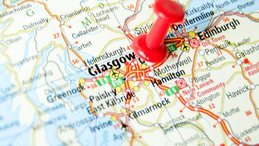 Close up photograph of a map of southern Scotland with a red push-pin in the location of Glasgow.