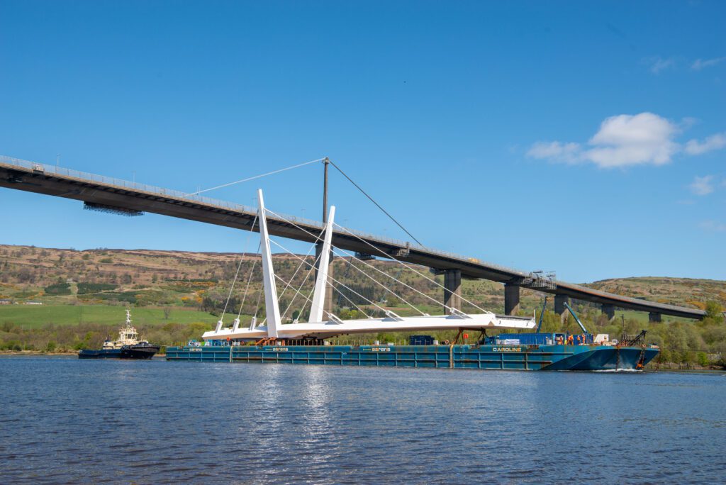 The bridge section travelling under the Erskine bridge on a barge, on its way to Renfrewshire.